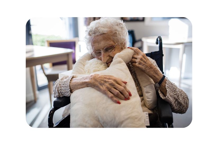 A woman in a wheelchair embraces HUG, the sensory companion.